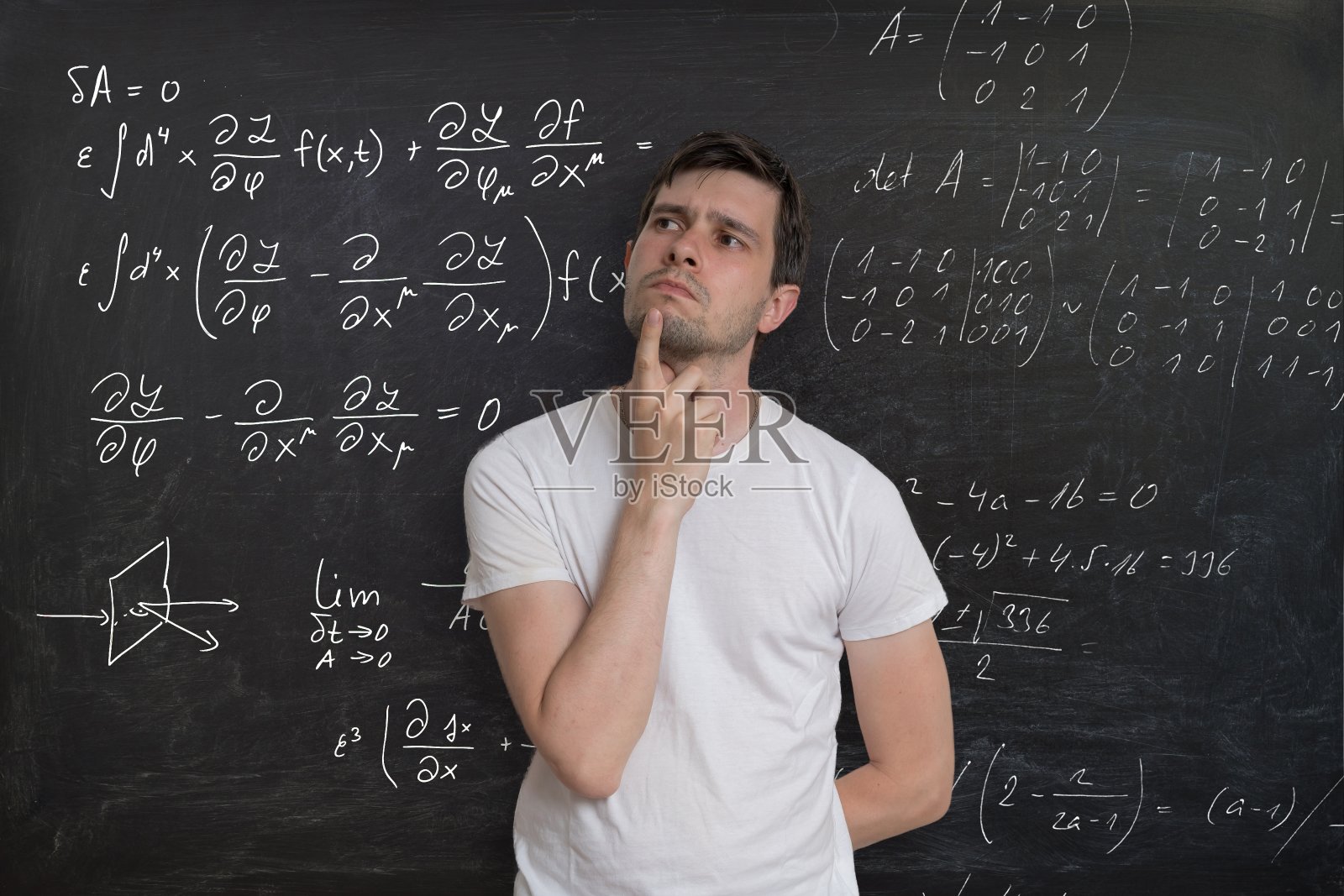 年轻的学生正在思考和解决数学问题。数学公式在黑板上的背景。照片摄影图片