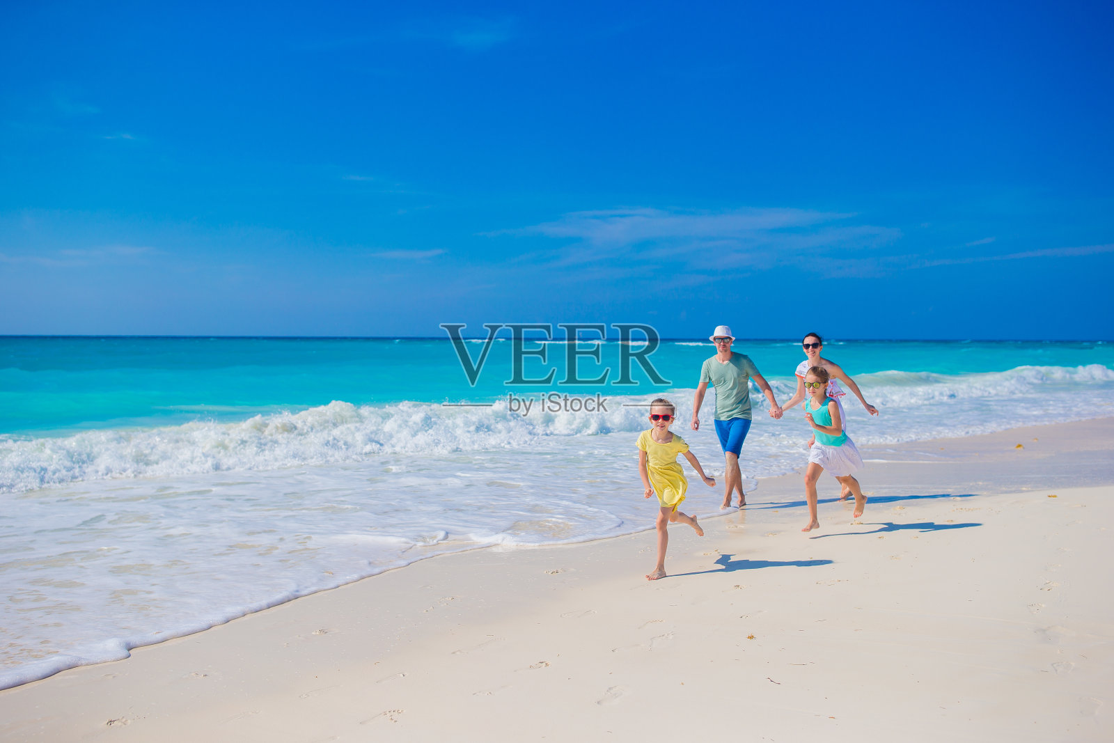 家庭在白色热带海滩有很多乐趣。父亲和孩子们在海边度假照片摄影图片