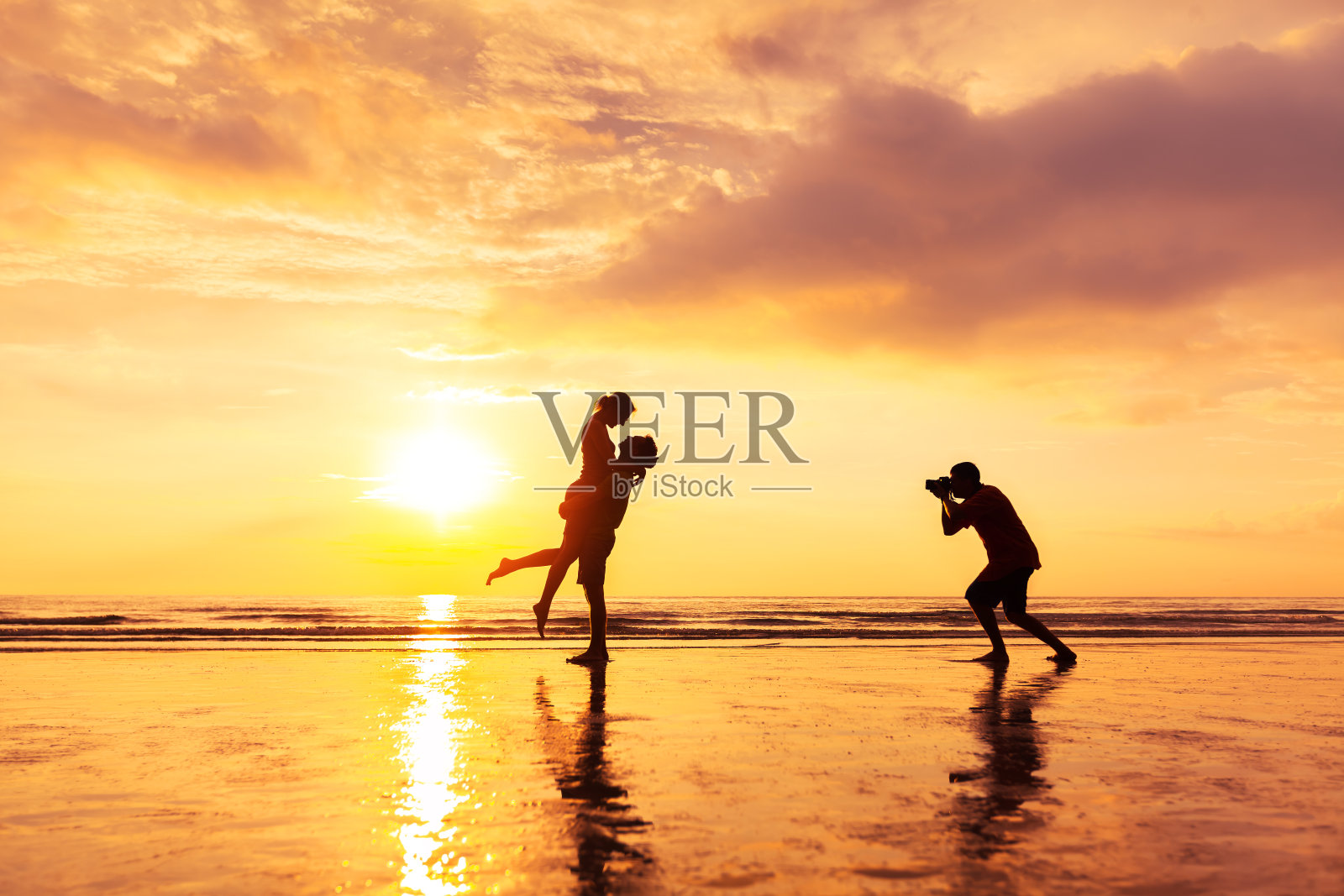 摄影师在夏天的海滩上拍摄一对相爱的夫妇照片摄影图片