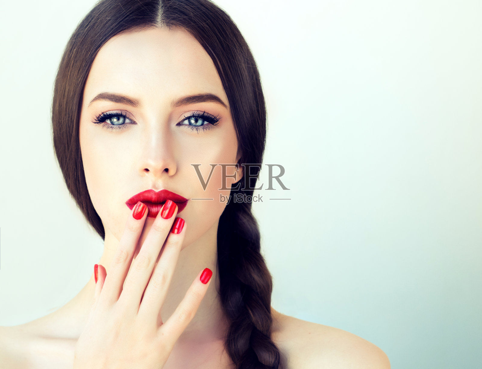 年轻的黑发女模特，梳着长长的辫子，修着红色的指甲。照片摄影图片