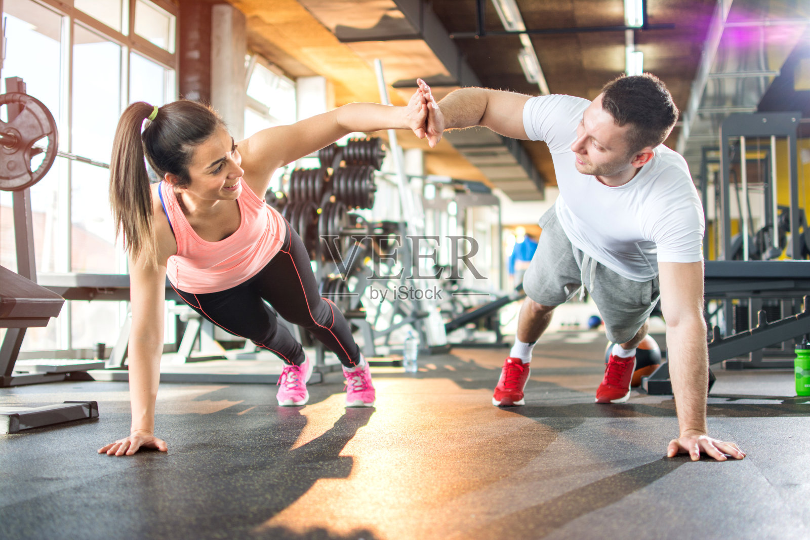 一对年轻的运动夫妇在健身房一起锻炼。照片摄影图片
