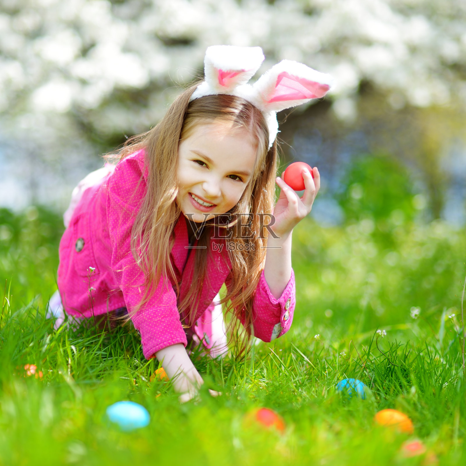 可爱的小女孩在盛开的春天花园里寻找复活节彩蛋照片摄影图片
