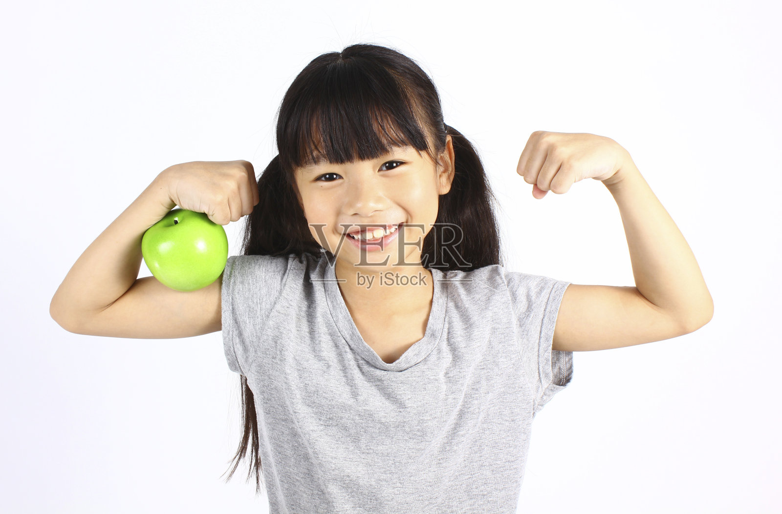 一个小女孩在炫耀苹果的时候展示了她的肌肉照片摄影图片