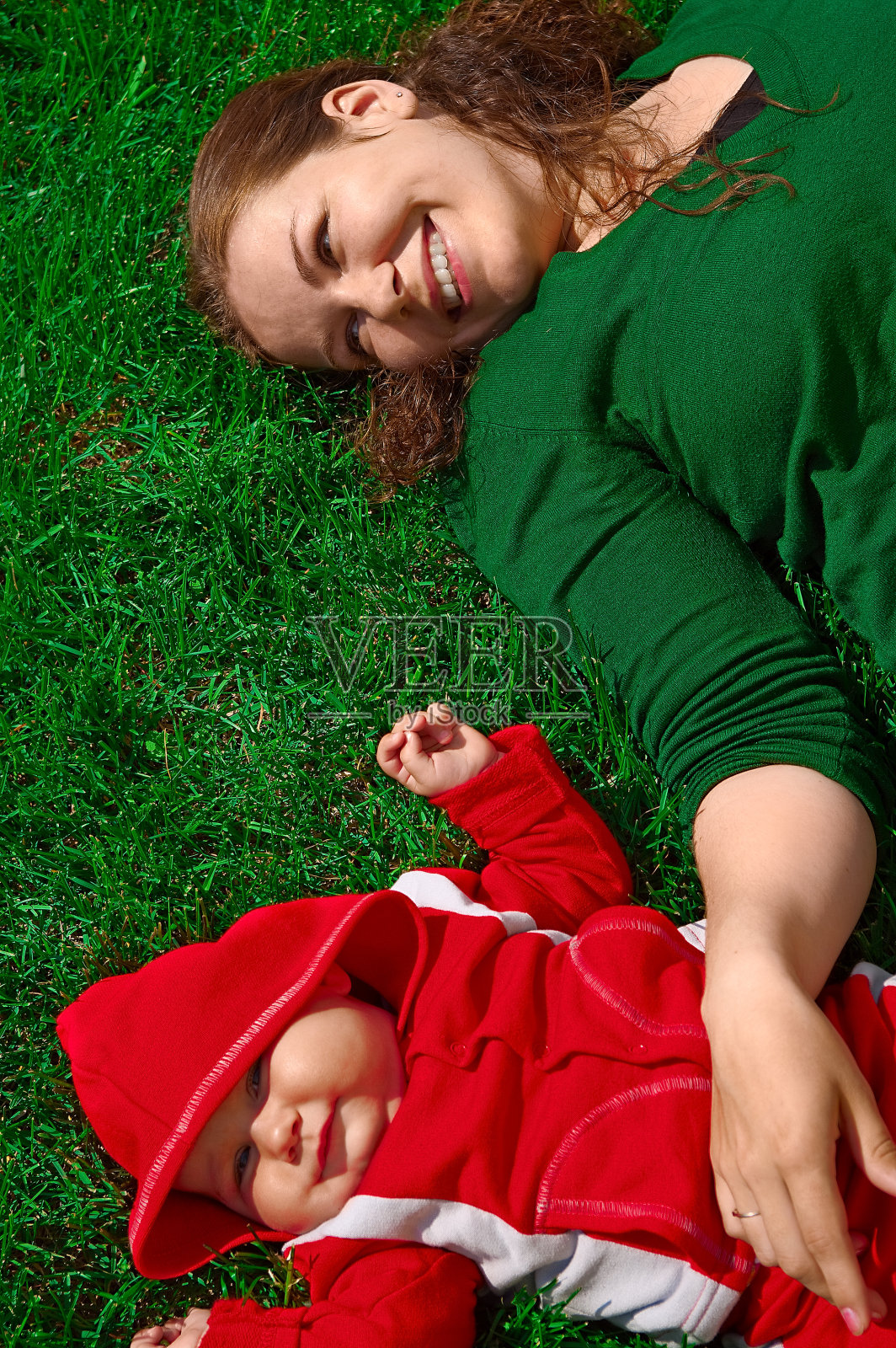 母亲和她的孩子躺在绿色的草地上照片摄影图片