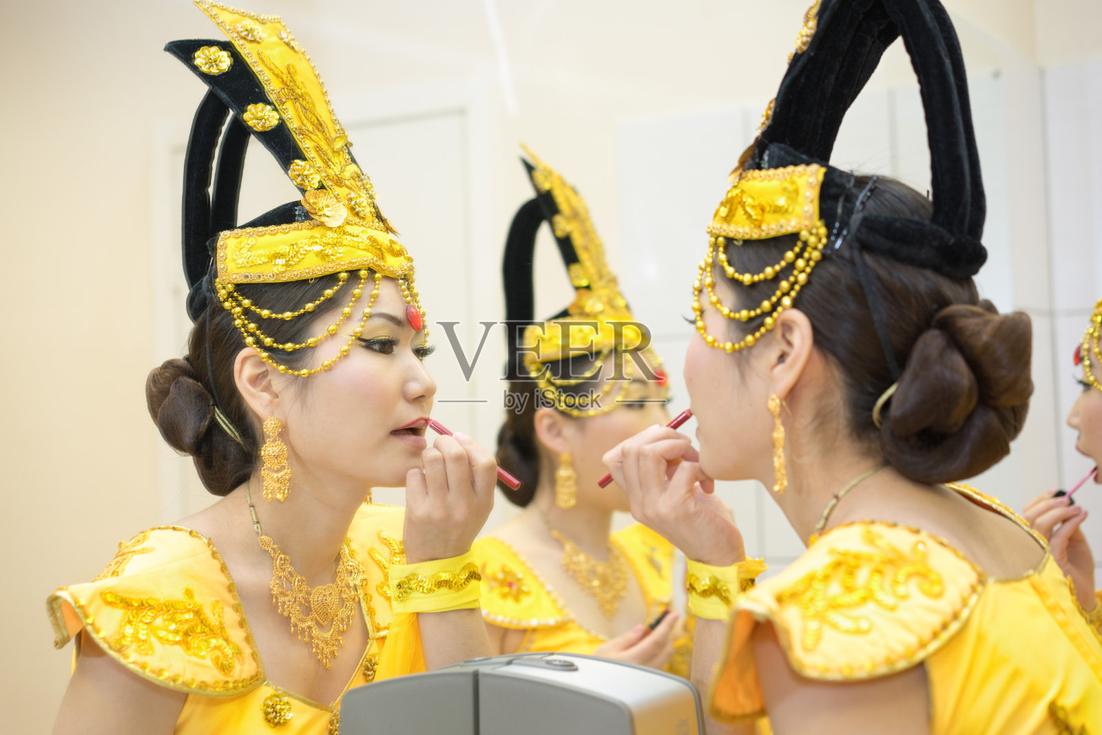 两个美丽的女演员穿着黄色的传统中国舞台服装在镜子前化妆。后台。照片摄影图片