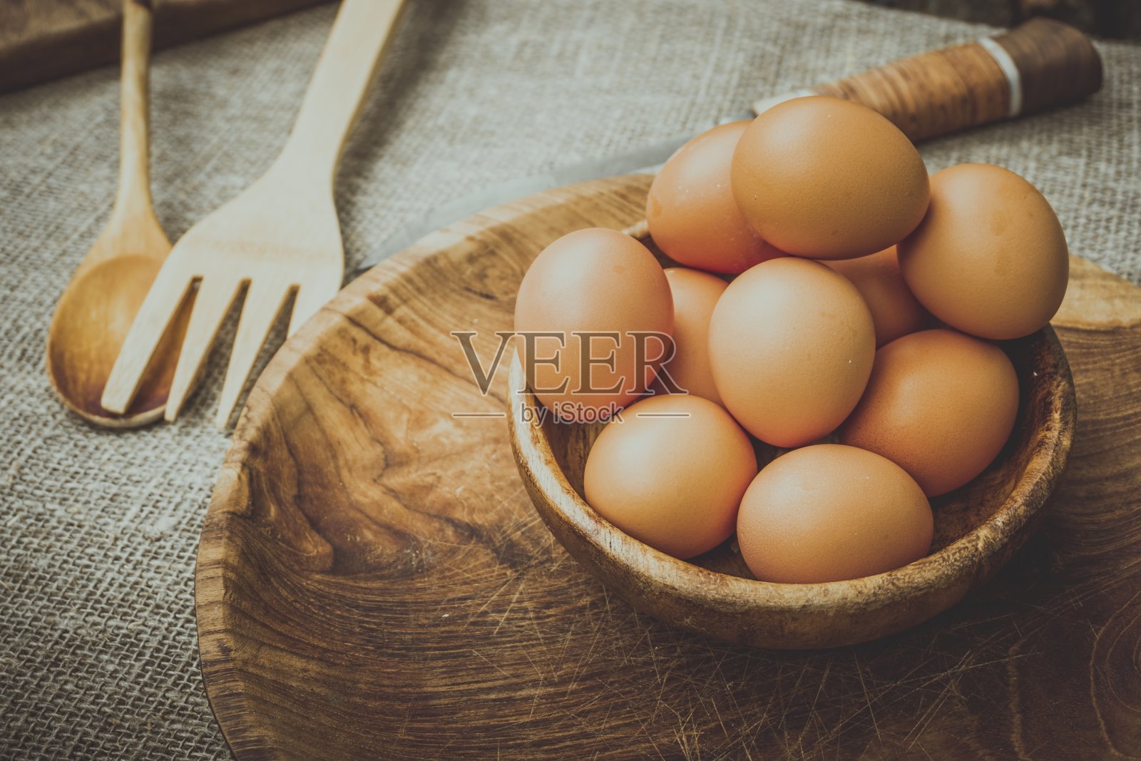 鸡蛋放在桌子上的木碗里。照片摄影图片