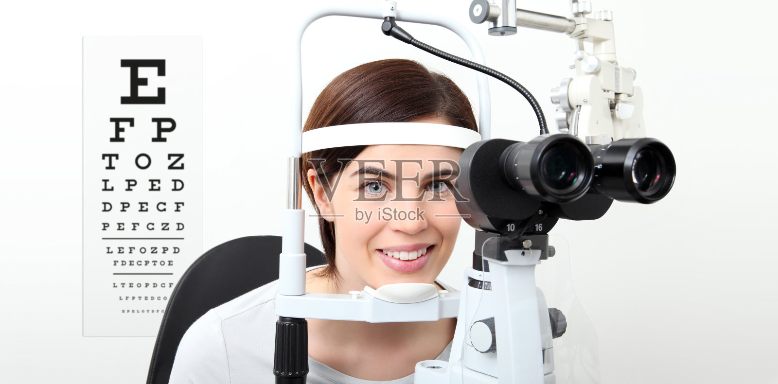 微笑妇女做视力测量裂隙灯和视力测试表在白色照片摄影图片