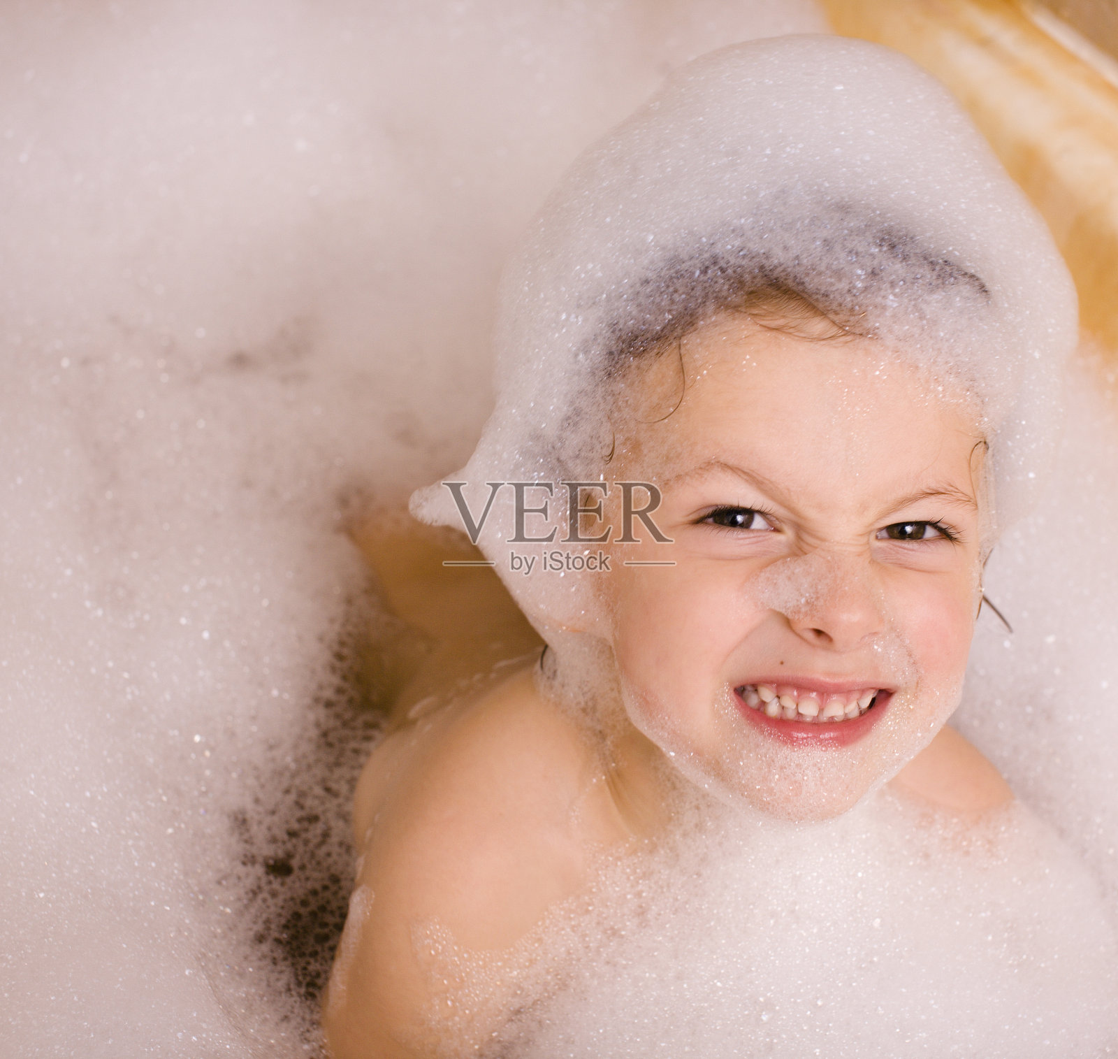 浴室里有泡沫的可爱小男孩照片摄影图片
