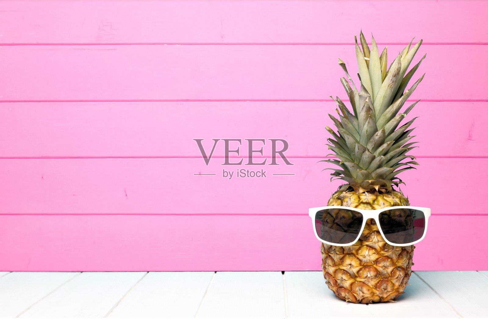时髦的菠萝配太阳镜，衬着粉红色的木头照片摄影图片