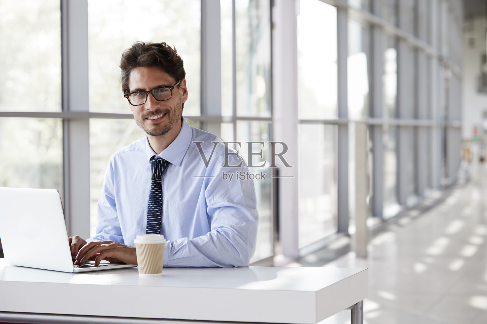 年轻的商人微笑着工作在他的笔记本电脑照片摄影图片