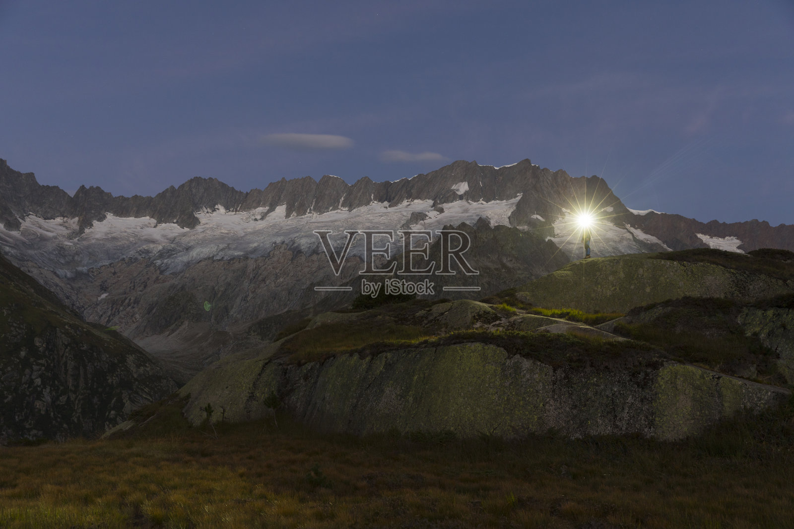 一个带着大灯的阿尔卑斯人站在瑞士阿尔卑斯山令人叹为观止的山景中照片摄影图片