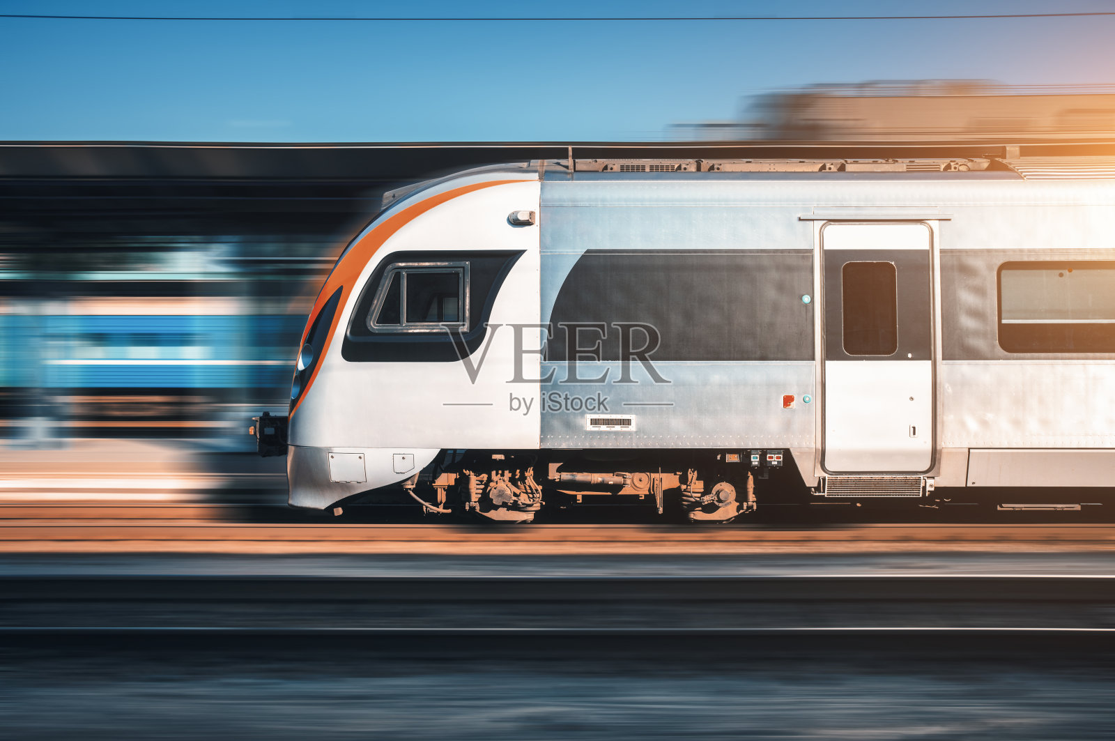 Speed train in motion at the railway station at sunset in Europe. Modern intercity train on railway platform with motion blur effect. Moving passenger train on railroad. Transportation. Vintage照片摄影图片
