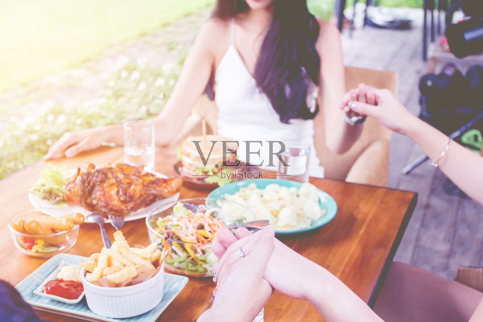前视图。群人餐饮理念。木桌上有烤鸡、沙拉、薯条照片摄影图片