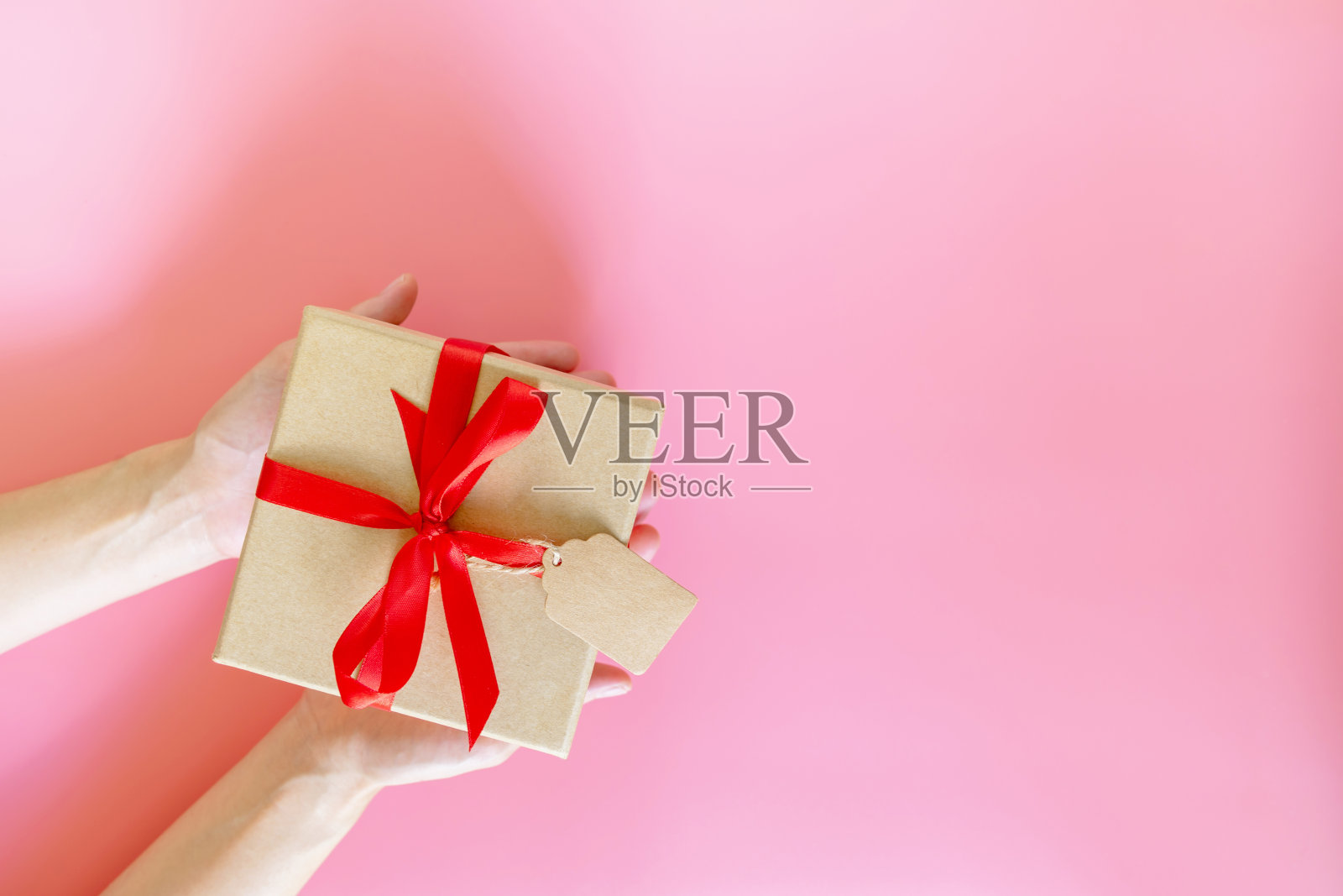 俯视图手握女人的棕色礼物盒子为新年粉红色柔和的颜色与空间。照片摄影图片