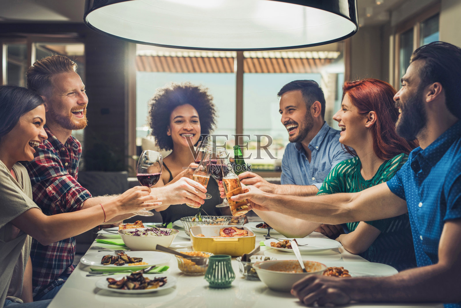 一群快乐的朋友在餐桌上互相敬酒。照片摄影图片