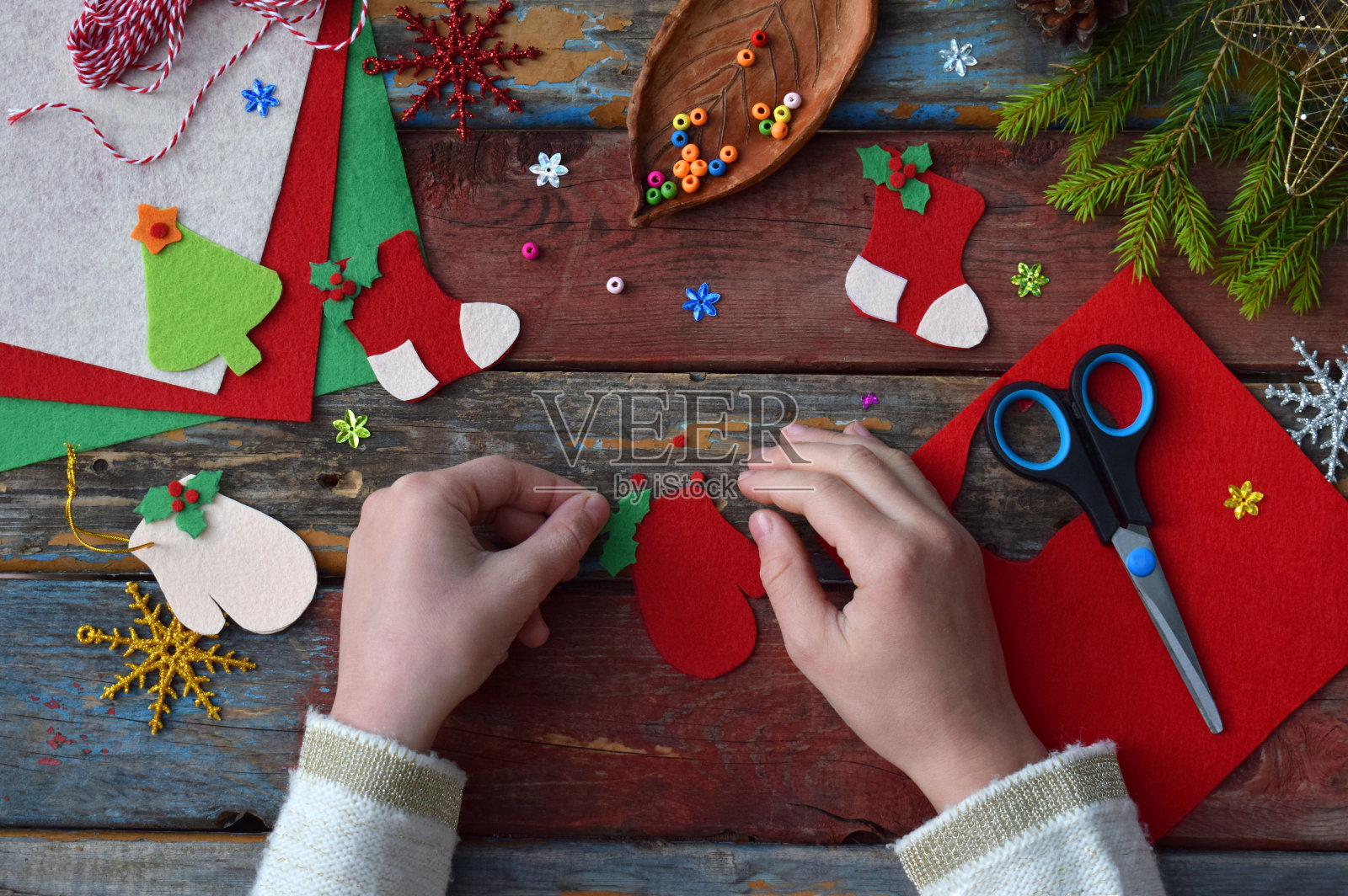 用自己的双手用毛毡制作手工制作的圣诞玩具。孩子的DIY的概念。制作圣诞树装饰品或贺卡。步骤3。装饰玩具照片摄影图片