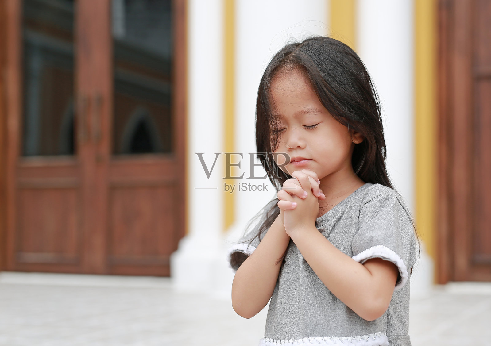 闭上眼睛祈祷的亚洲小女孩。照片摄影图片