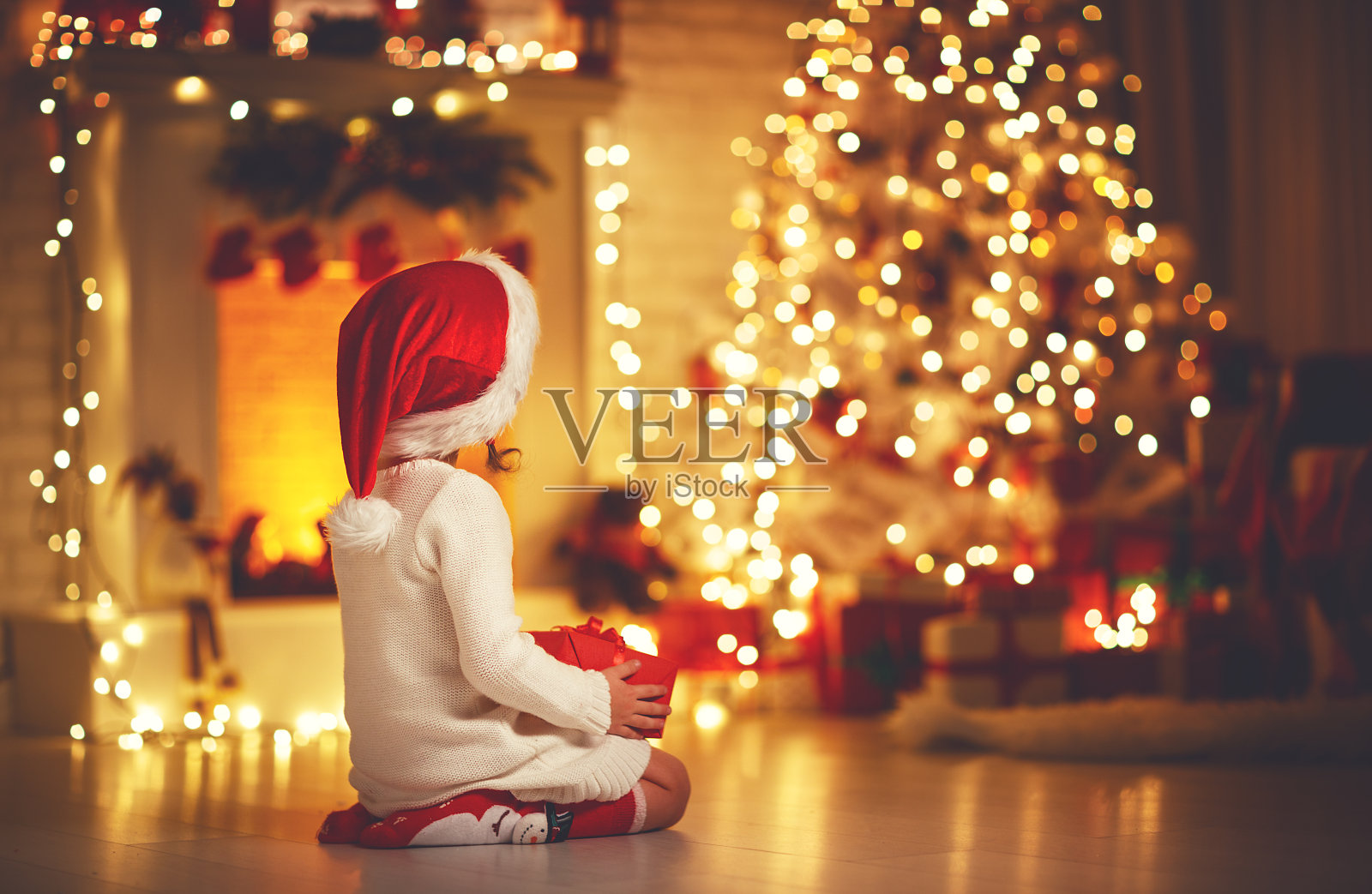 圣诞节前夕，一个小女孩坐在圣诞树前照片摄影图片