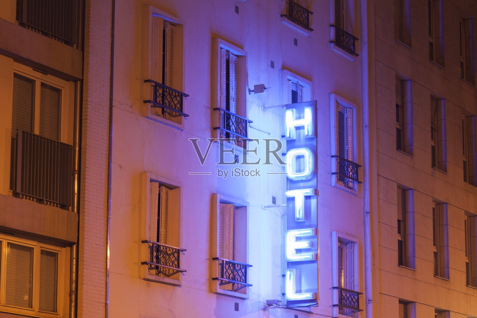 巴黎的建筑立面在夜晚用霓虹灯照亮酒店的标志照片摄影图片