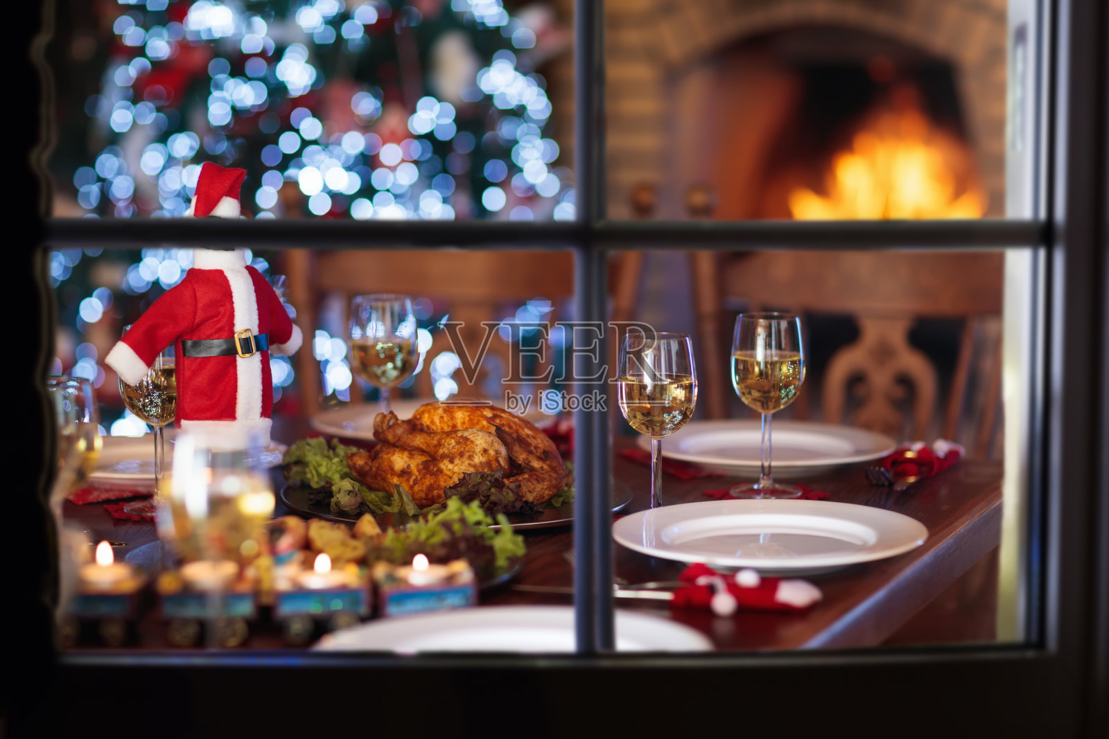 在壁炉和圣诞树旁吃圣诞晚餐。照片摄影图片