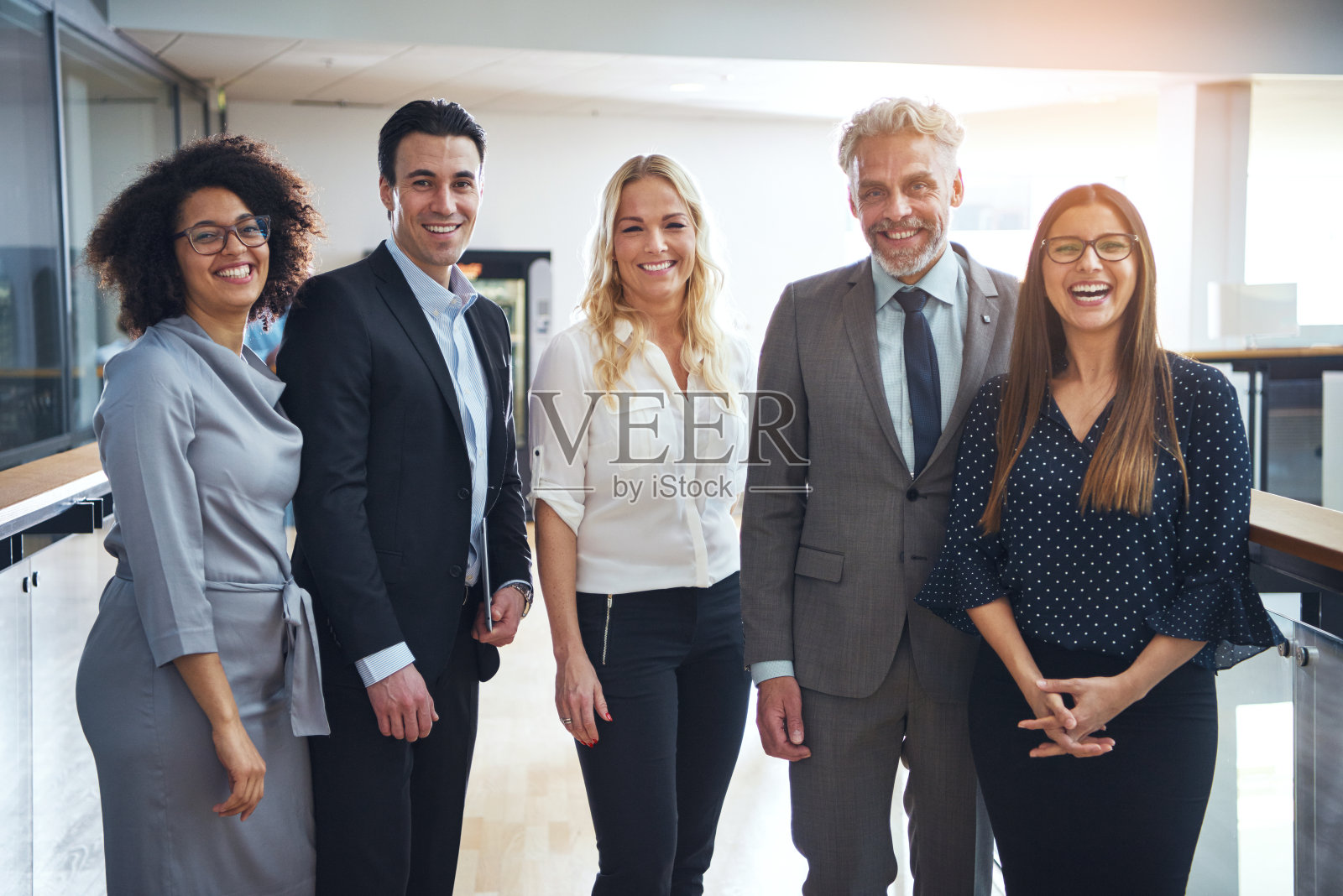 一群不同的同事微笑着一起站在办公室里照片摄影图片