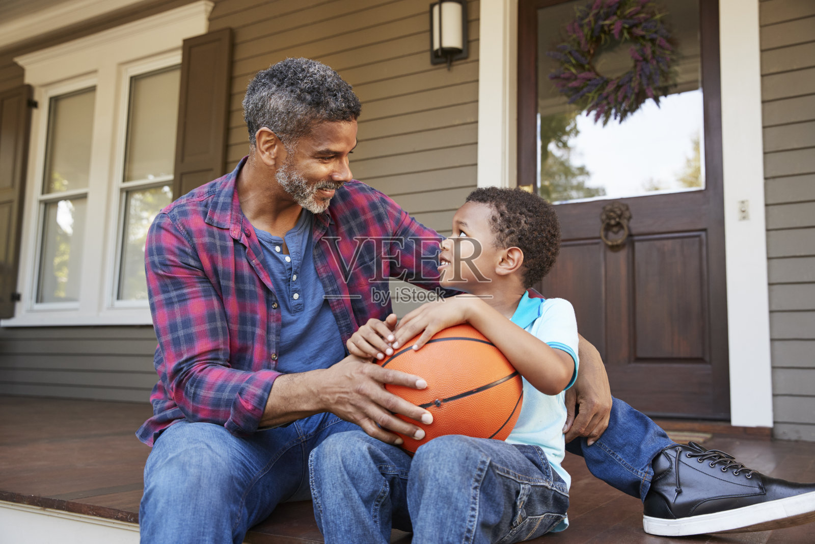 父亲和儿子在家的门廊上讨论篮球照片摄影图片
