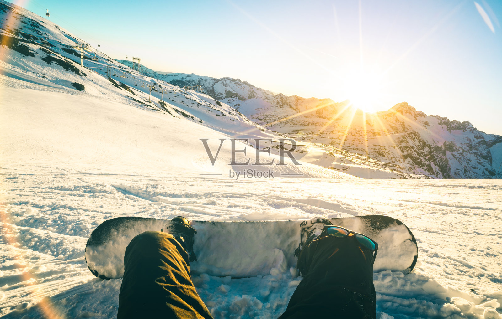 滑雪板坐在日落在法国阿尔卑斯山滑雪胜地放松的时刻-冬季运动概念与冒险的家伙在山顶上准备骑下来-腿视点与蓝绿色和橙色滤镜照片摄影图片