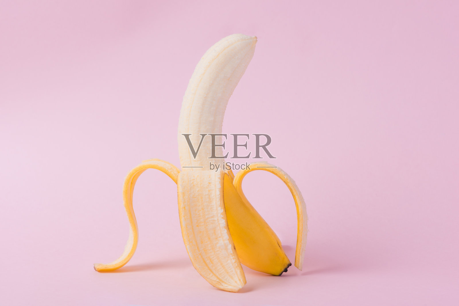 新鲜去皮的香蕉，粉红色的背景照片摄影图片