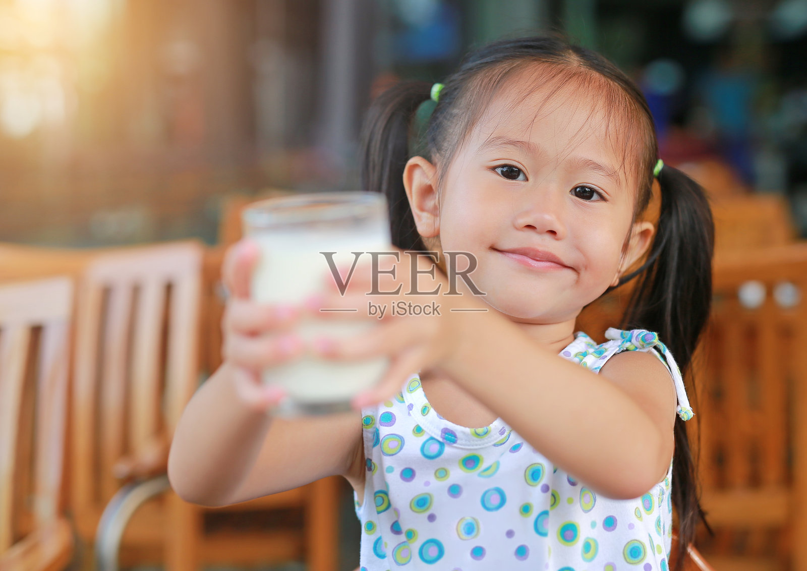早上在餐厅微笑的亚洲女孩给你一杯牛奶。健康早餐理念。照片摄影图片