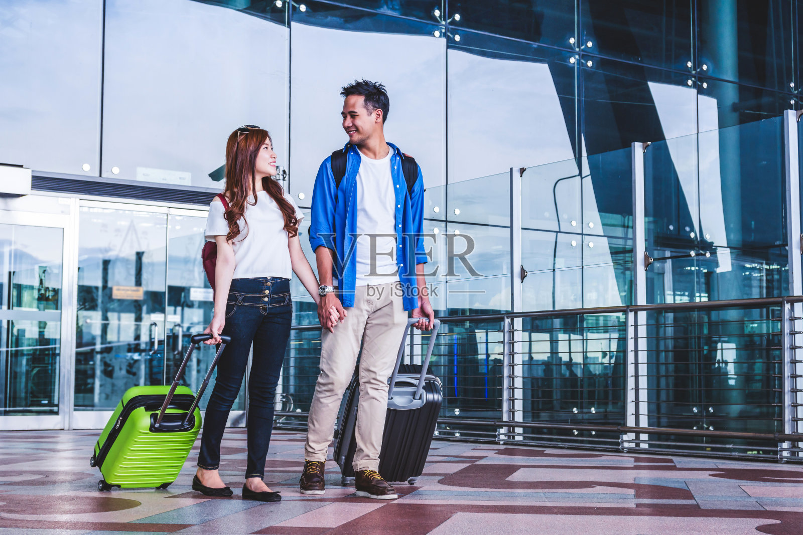 带着行李箱的亚洲夫妇在机场。带科技理念的情侣旅游交通。照片摄影图片