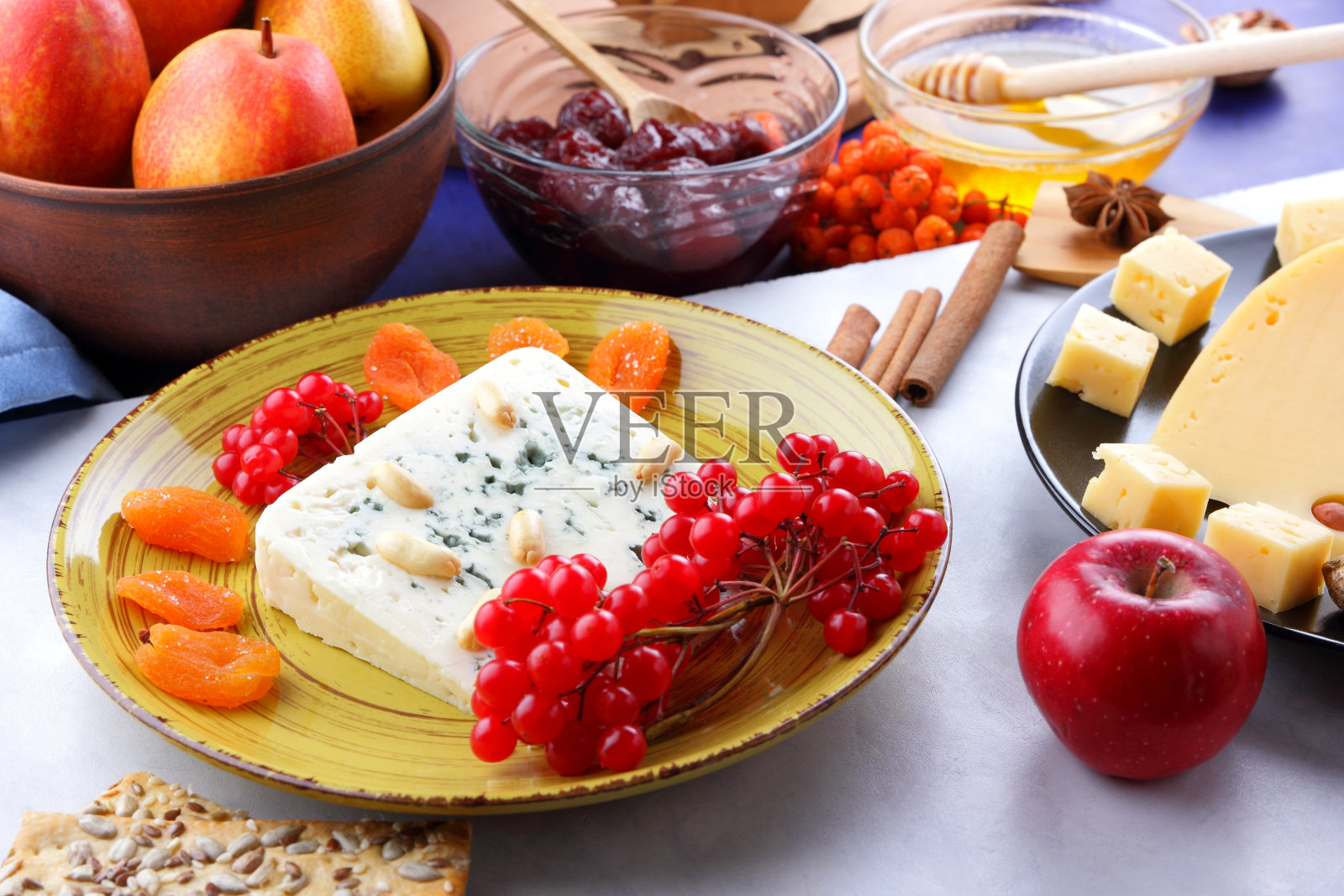 发霉的奶酪、水果、深蓝色背景上有孔的硬奶酪、黑色盘子上的奶酪、水果、坚果、蜂蜜、果酱、圣诞晚餐、五彩缤纷的背景、复古风格照片摄影图片