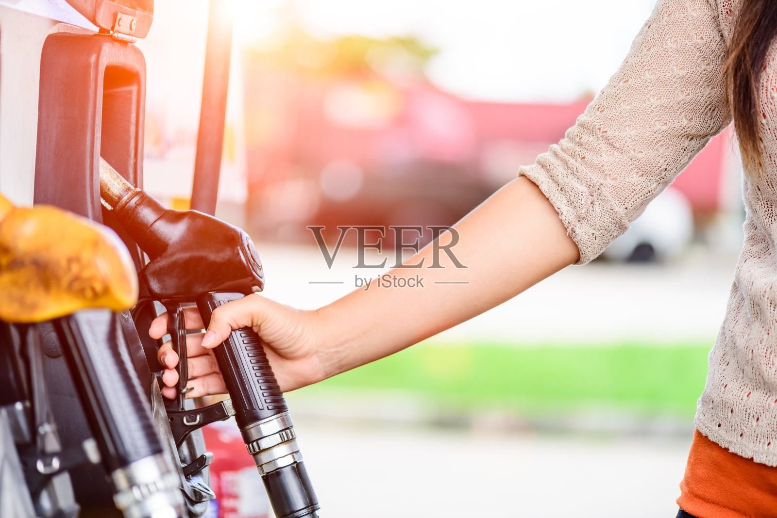 一个女人的手在一个加油站的燃油泵的特写。照片摄影图片