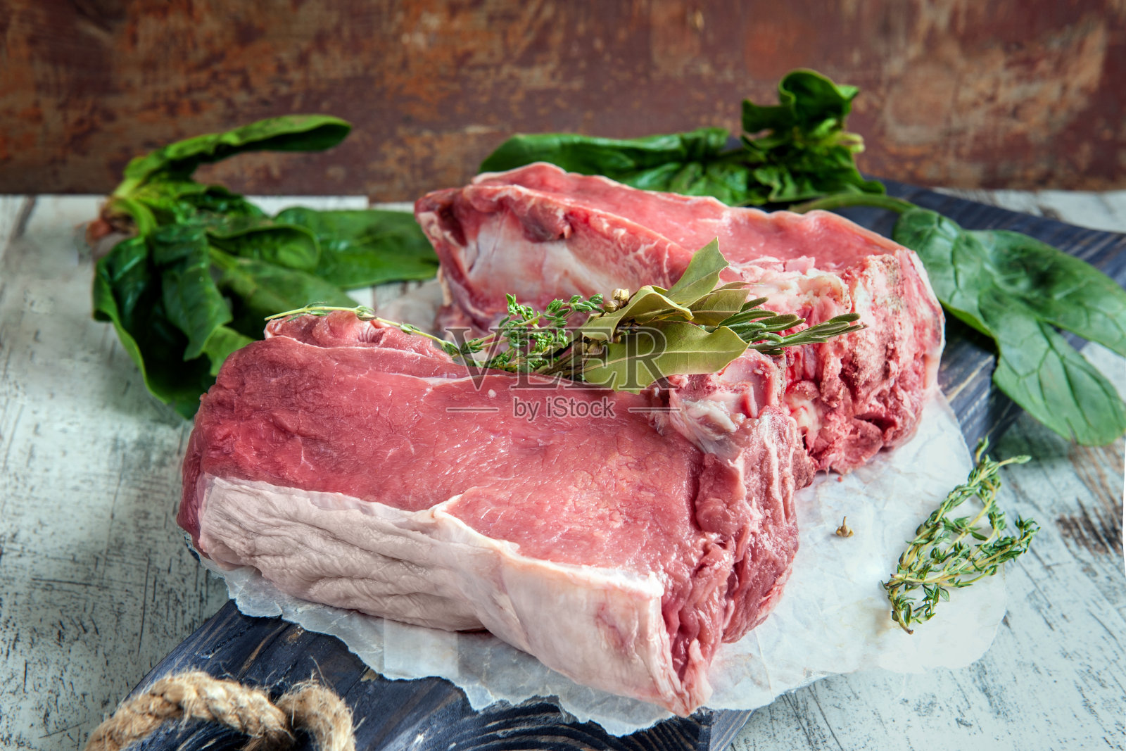 将切好的牛肉放在木砧板上烤，用菠菜、迷迭香和普罗旺斯香草做腌料照片摄影图片
