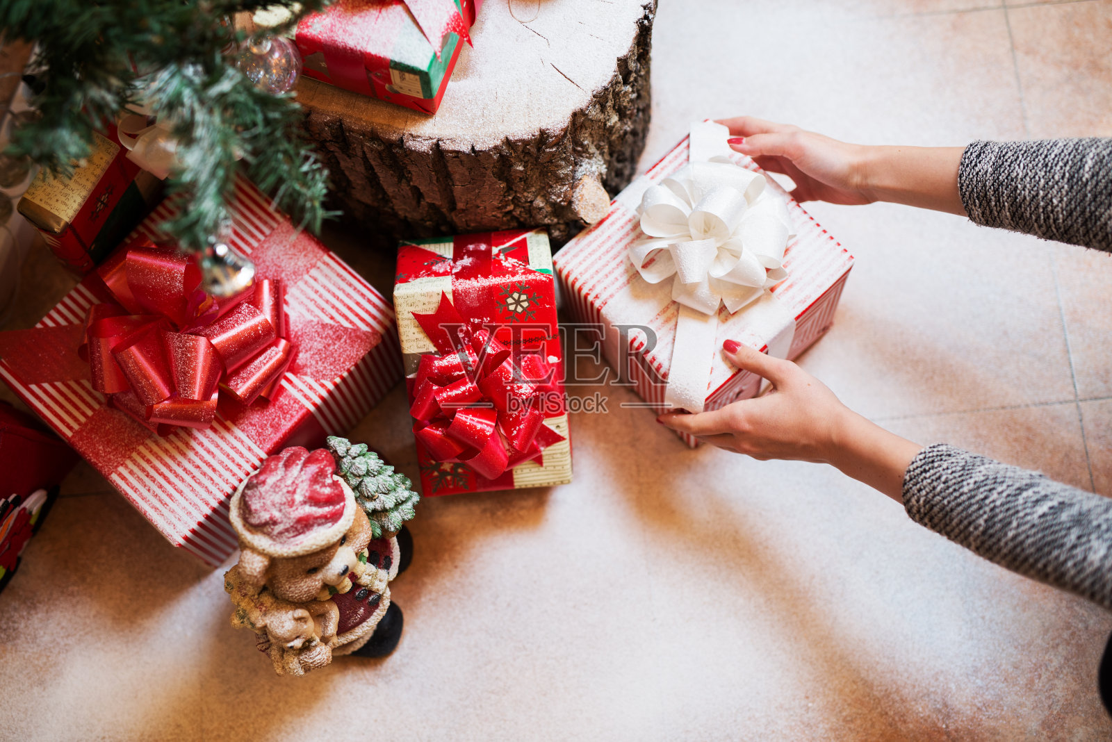 近女人的手放下礼物盒下的圣诞树。照片摄影图片