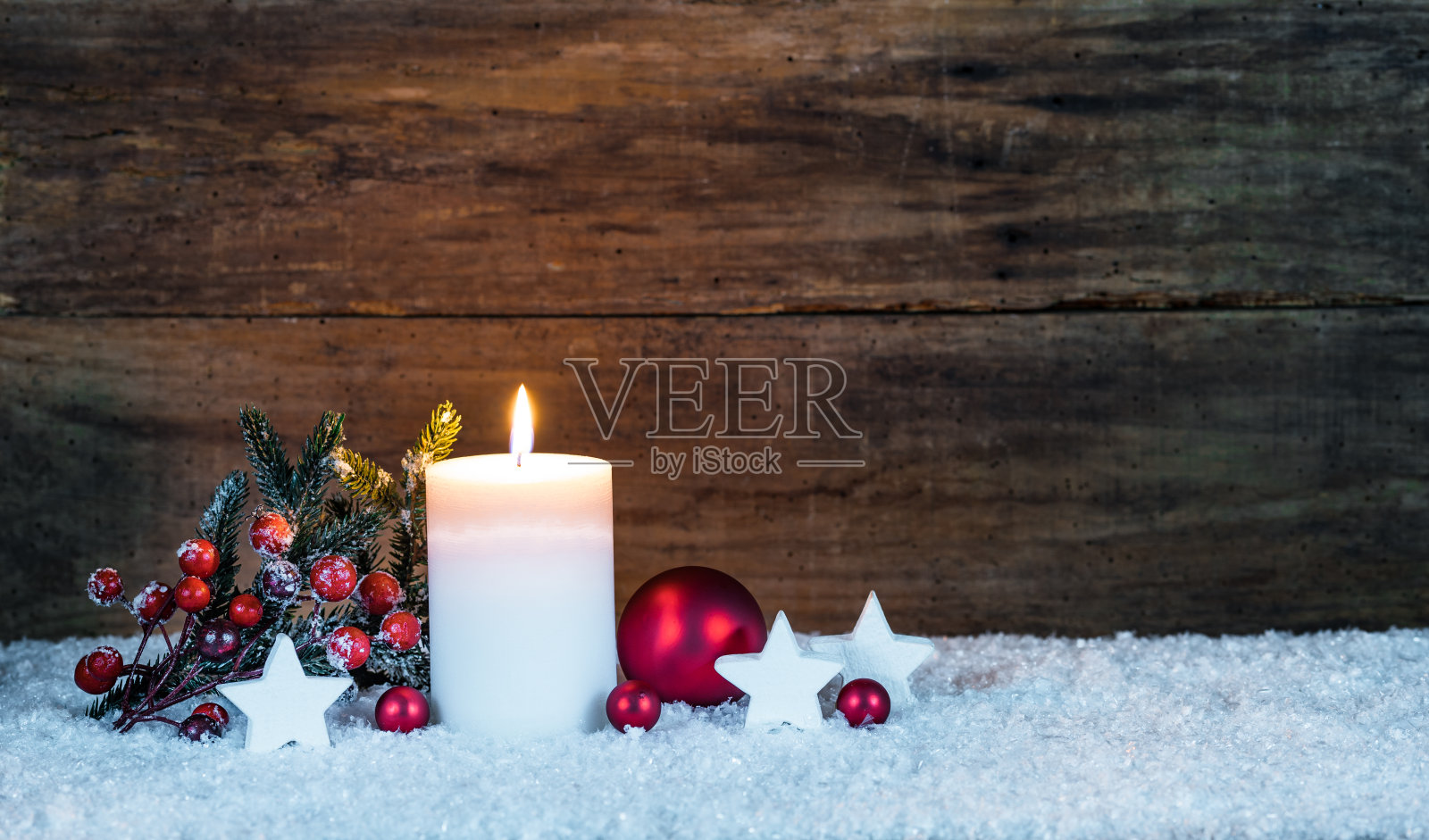 传统的圣诞装饰用白色的蜡烛和红色的装饰品在雪与木制的背景照片摄影图片