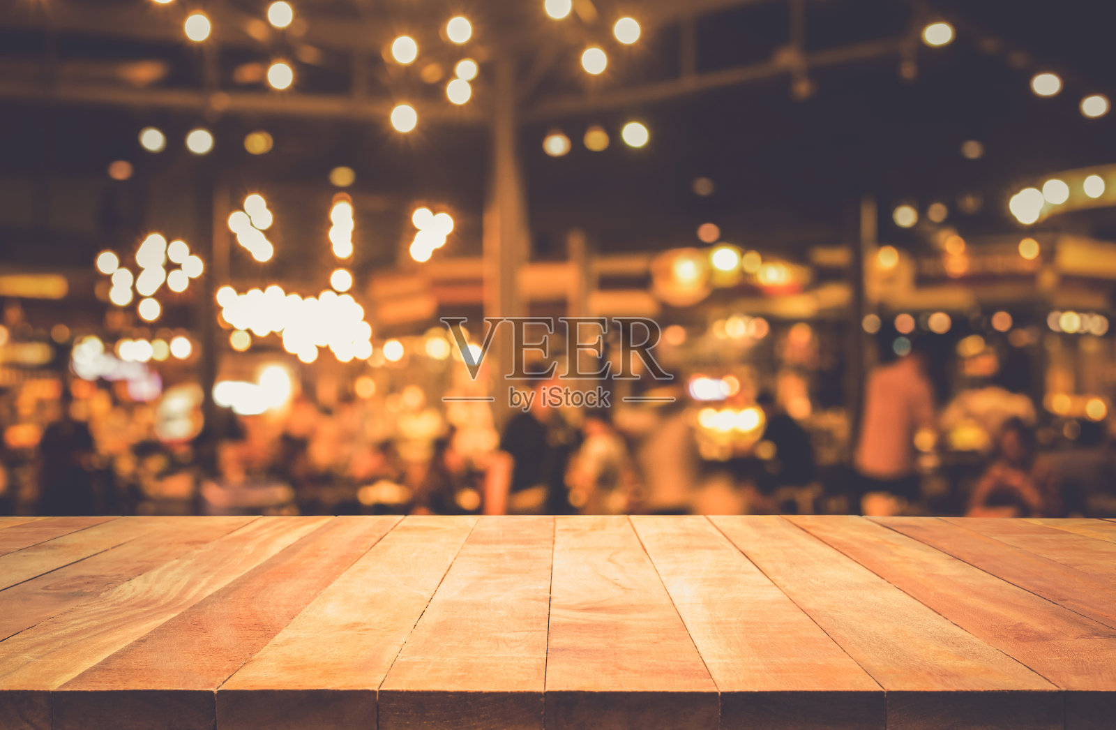 木桌与模糊的灯光散景在黑暗的夜晚咖啡馆照片摄影图片