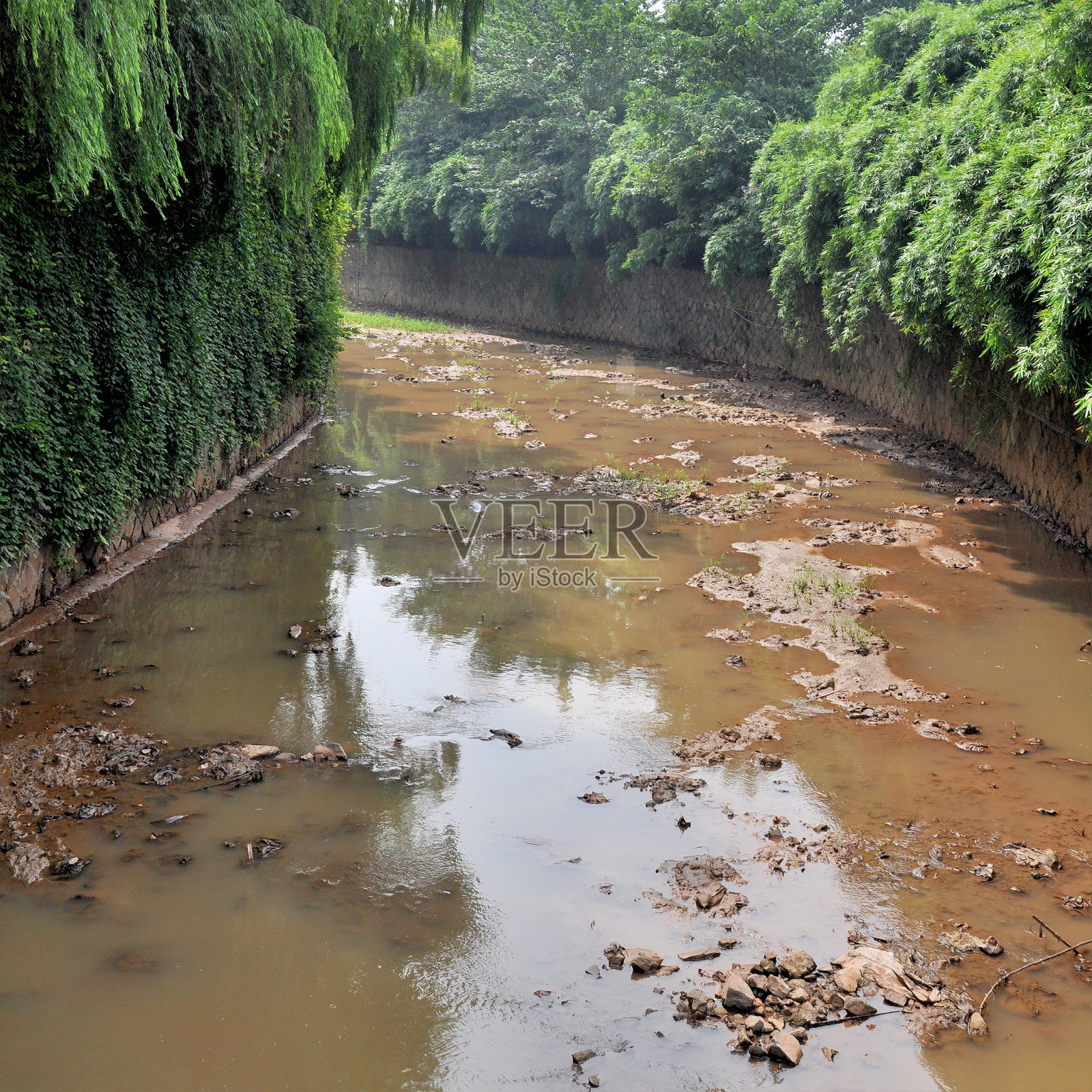 城市中的一条被污染的河流。有毒的水从下水道流出照片摄影图片
