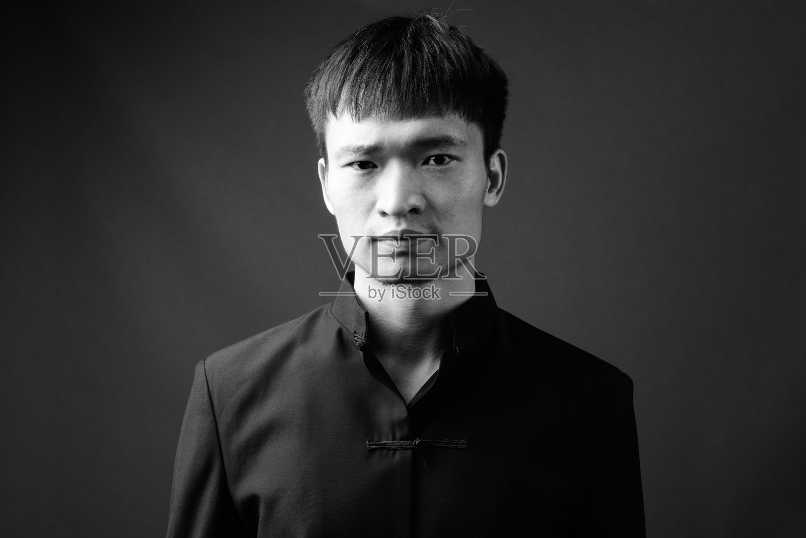 在灰色背景下穿着传统服装的年轻中国男子照片摄影图片