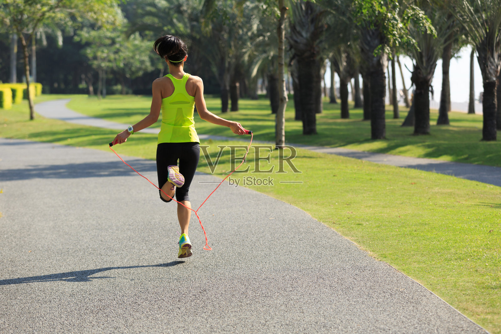 一个年轻的健身女子在热带公园跳绳照片摄影图片