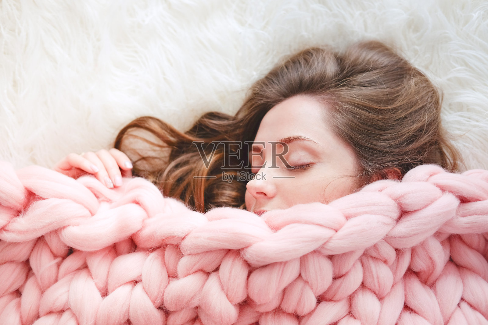 年轻女子与长棕色头发睡在温暖针织桃色扔毯子照片摄影图片