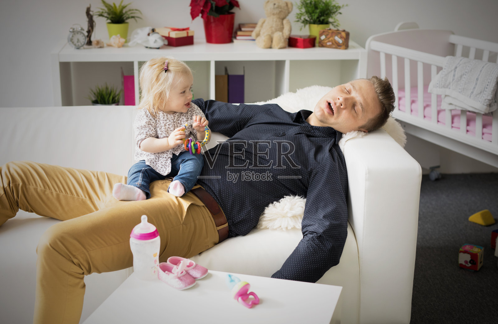 疲惫的父亲抱着孩子睡在他的腿上。照片摄影图片