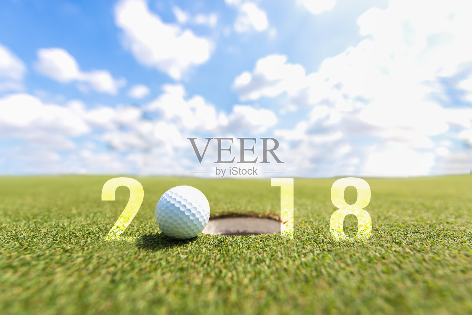 高尔夫运动概念形象。2018年新年快乐。高尔夫球在绿色的球道上，蓝天为背景。假日及运动概念照片摄影图片