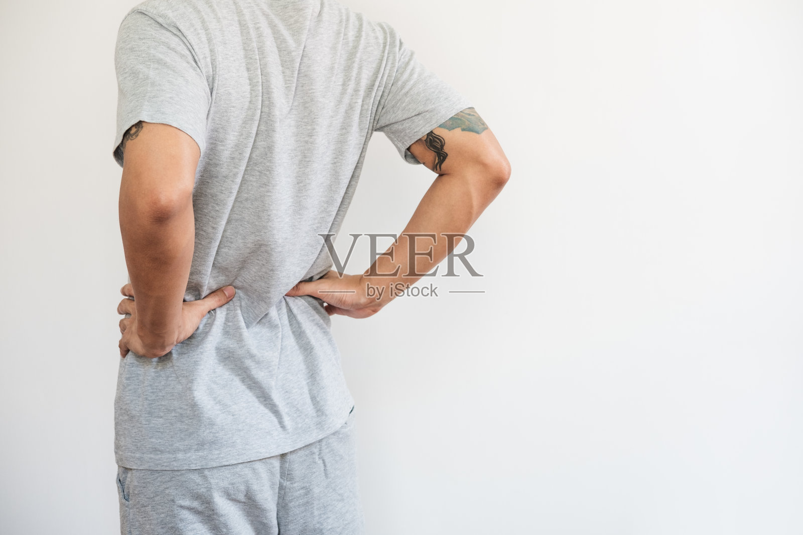 一个男人在摸他的背。背部疼痛，背部疼痛和腰部疼痛，在白色的背景照片摄影图片