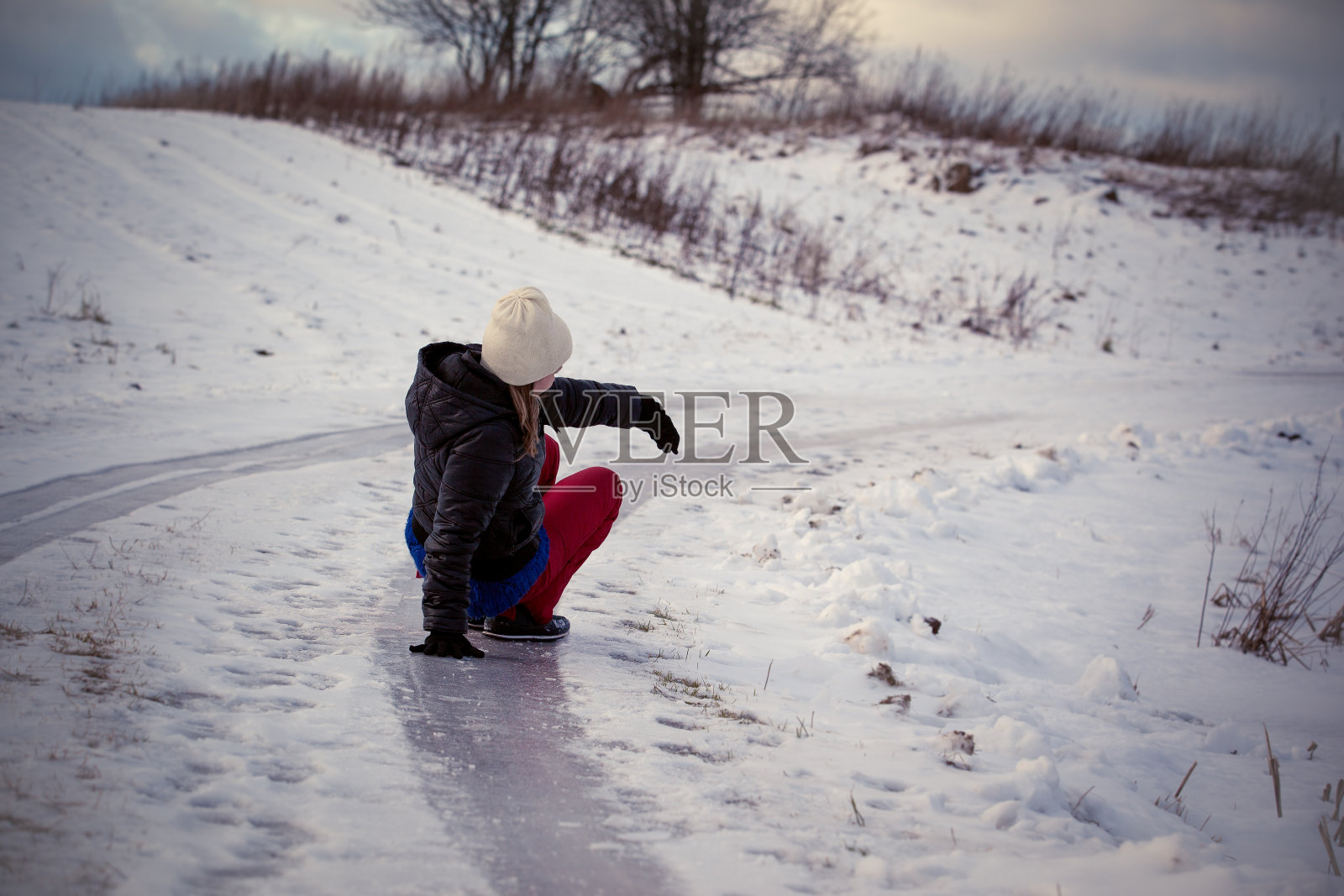 在寒冷的冬日里，在乡村道路上滑倒在光滑的冰雪上照片摄影图片