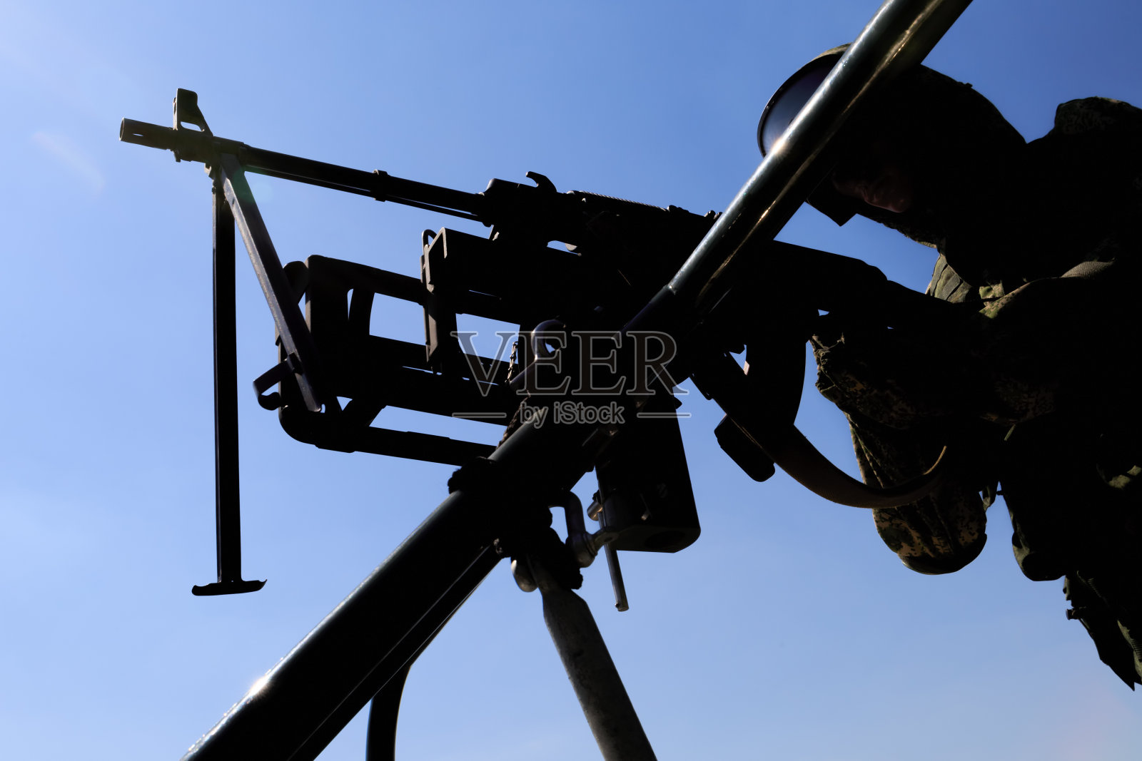 士兵的人体模型站在蓝天的背景上，带着一挺机关枪照片摄影图片