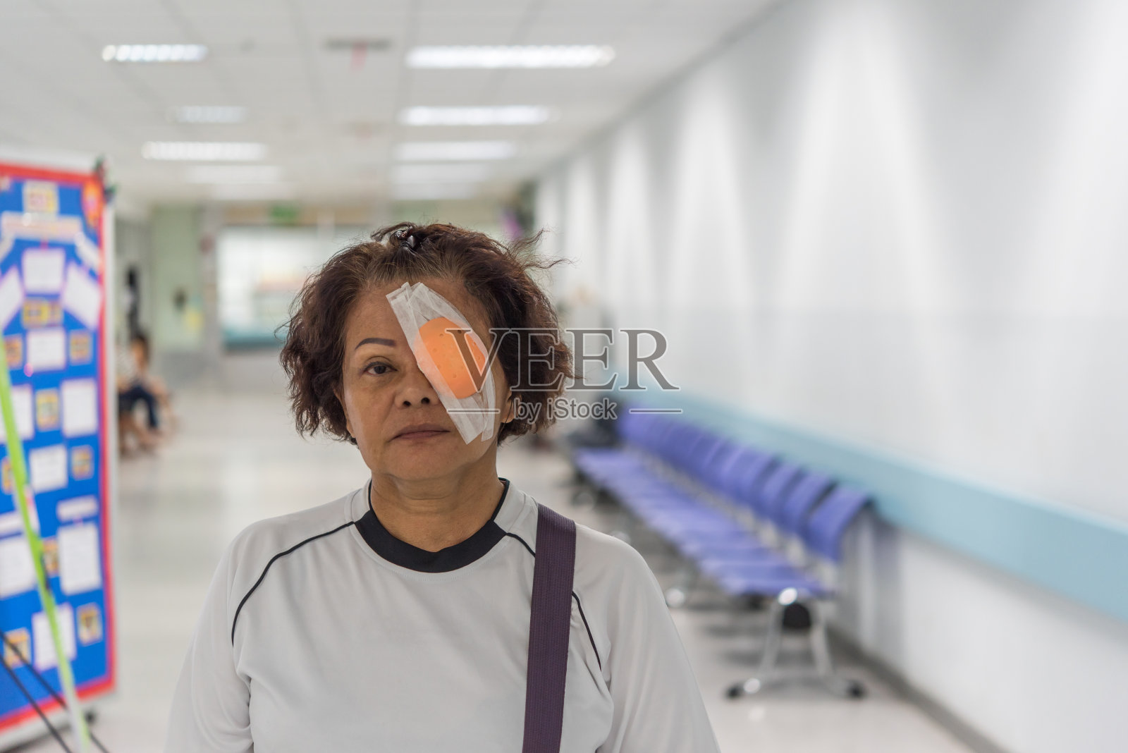 患者亚洲老年妇女60多岁与黑头发和脸上皱纹显示她的眼睛与眼垫和眼罩后角膜手术(lasik)由眼科医生在医院，美容保健概念照片摄影图片