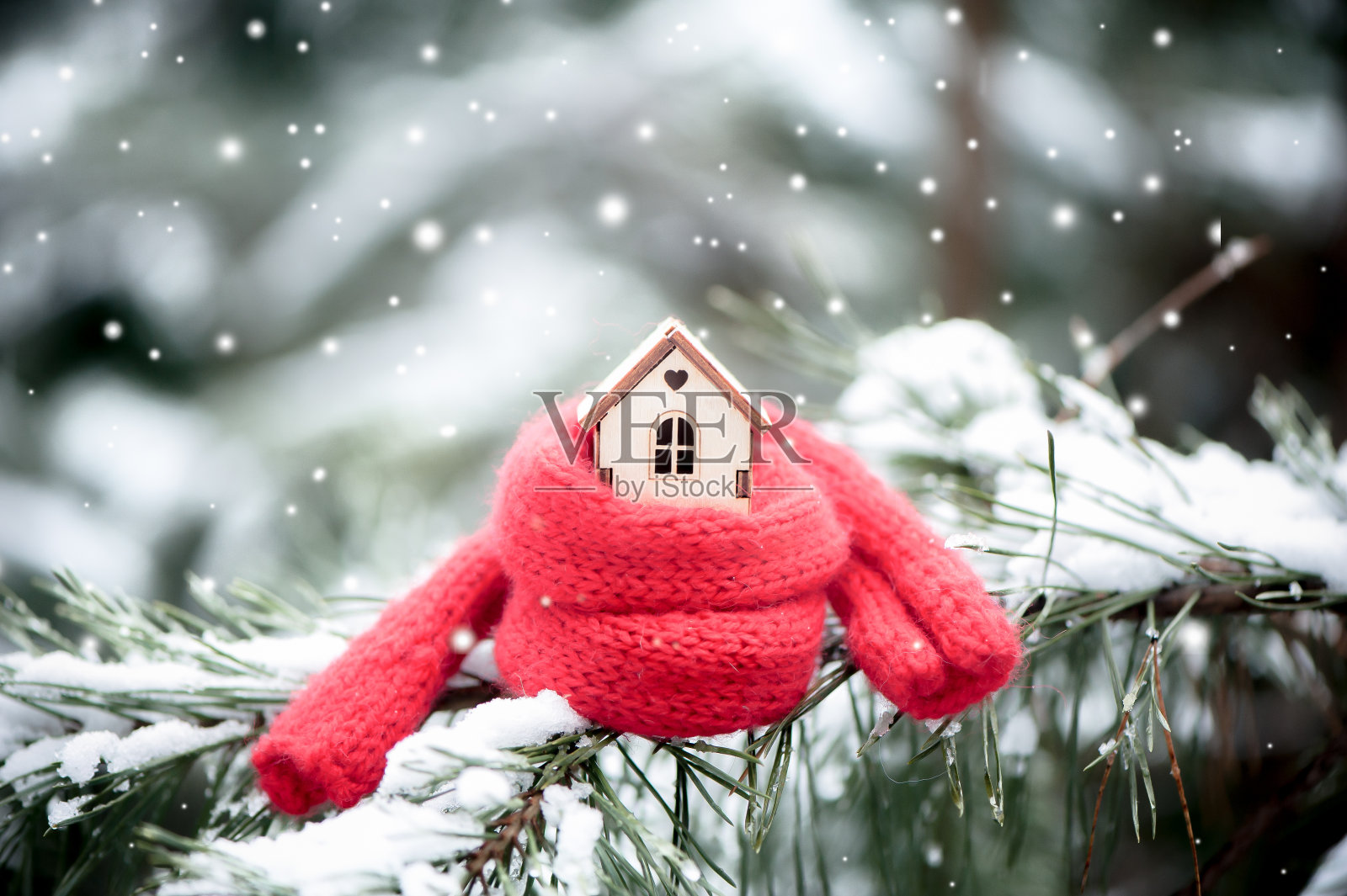 圣诞玩具屋裹着一条暖和的围巾，正在下雪。以一棵真正的冷杉为自然背景，在雪中调色。冬天，圣诞节，新年，照片摄影图片