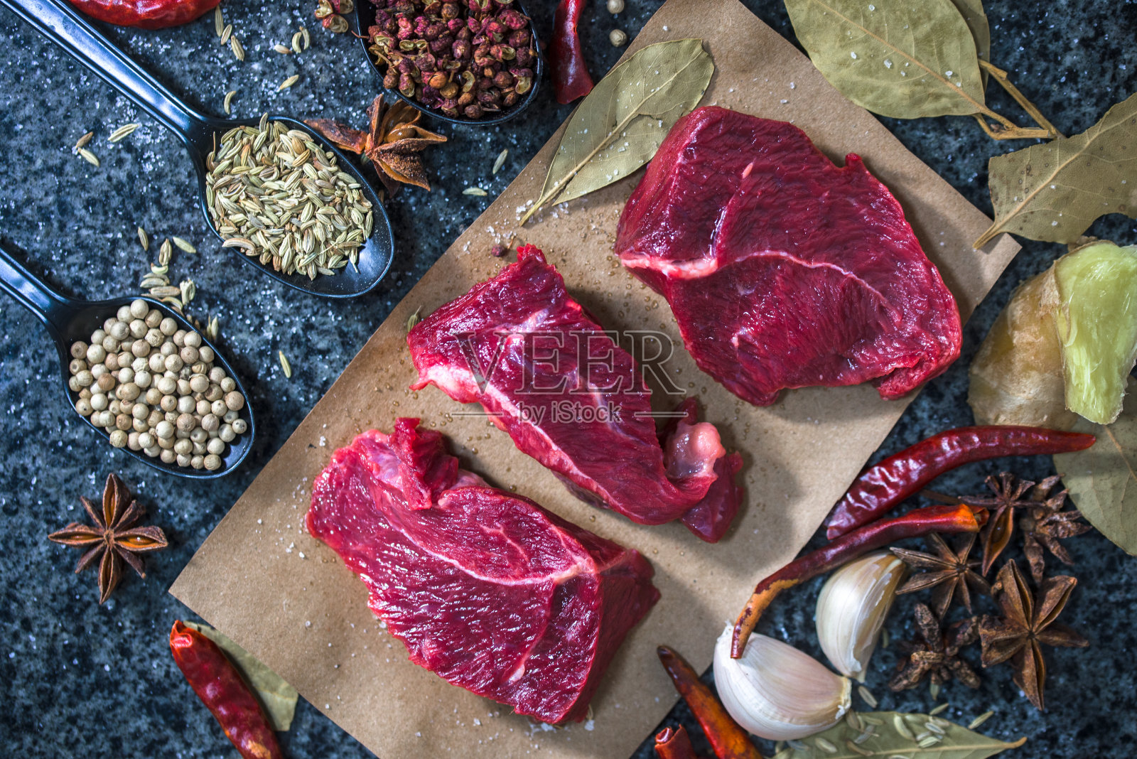 生肉。生牛排放在切菜板上，加入迷迭香和香料。照片摄影图片