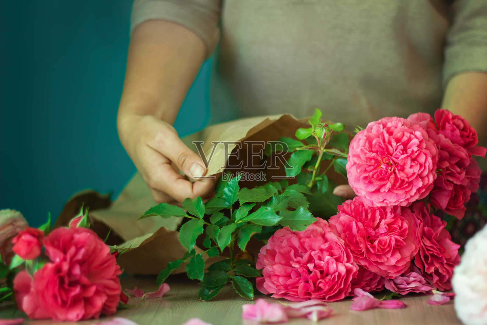 卖花的女孩用纸把漂亮的粉红色玫瑰包起来照片摄影图片