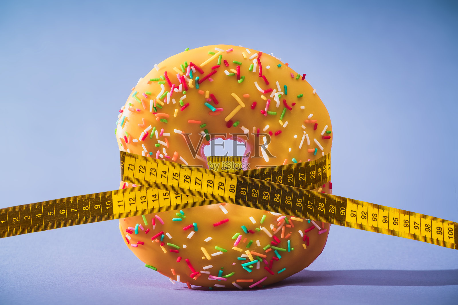 饮食。减肥。用卷尺系甜甜圈。照片摄影图片